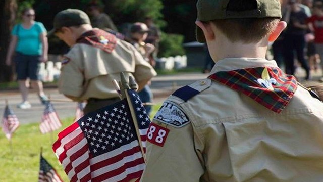 A_boy_scout_places_small_American_flags_at_the_graves_in_the_Gettysburg_National_Cemetery